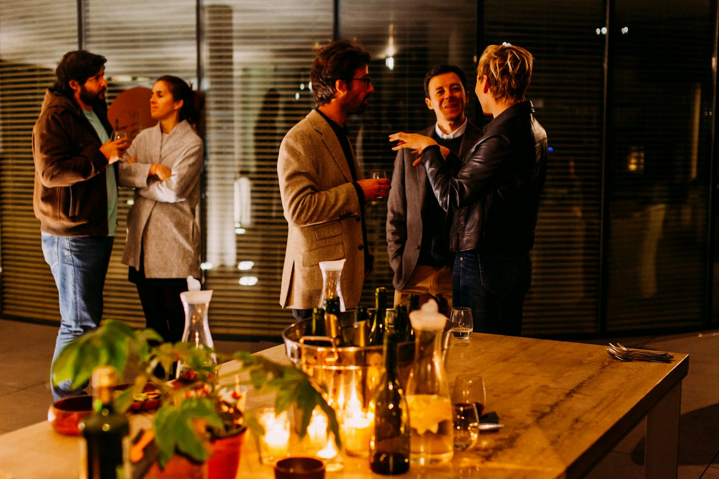 Invitados conversando con copas de vino en un evento nocturno